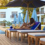 A woman sitting on a relaxing chair by a pool in a hotel, surrounded by lush greenery and a serene atmosphere in Sri Lanka